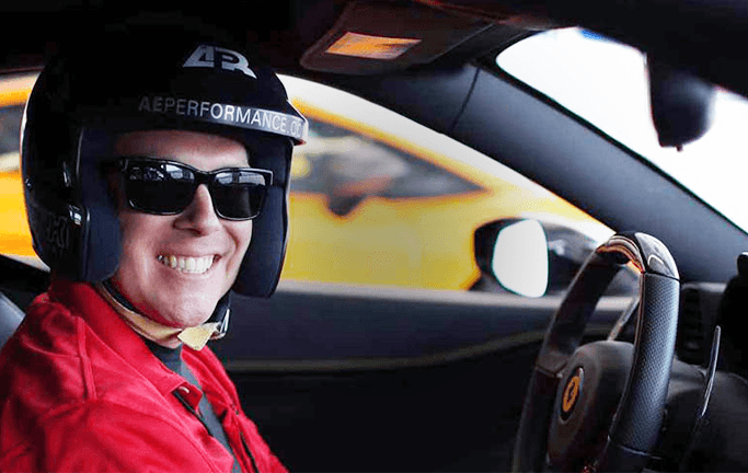 Happy customer smiling in a helmet behind the wheel of a car – over 400,000 satisfied drivers